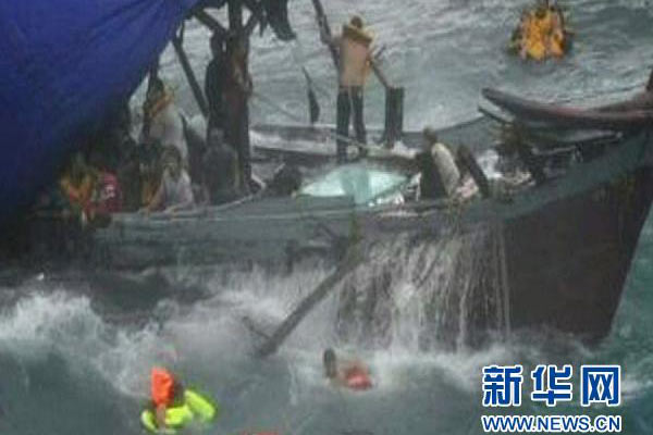 这张2010年12月15日发布的视频截图显示, 在澳大利亚北部圣诞岛海岸附近触礁的难民船上的船员在等待救援。
